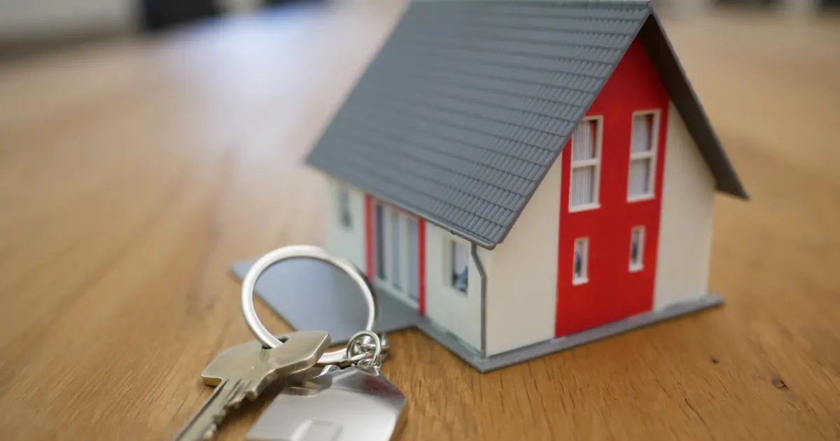Clés posées sur un contrat d'assurance avec un appartement en arrière-plan